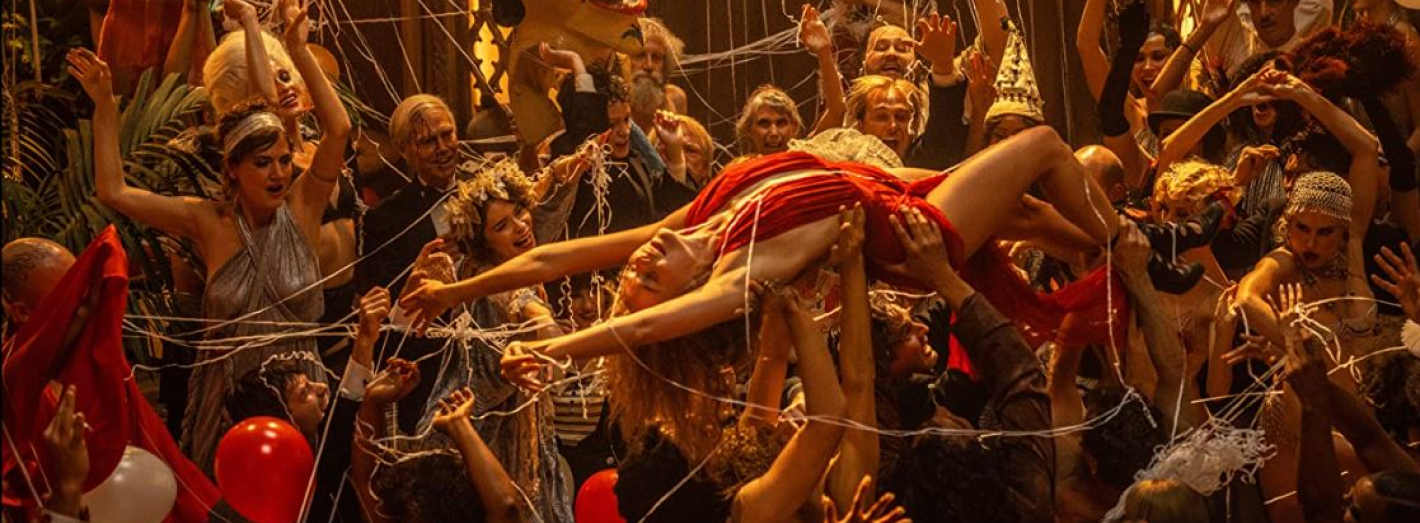 Foto do artigo, cena de uma festa, com a Margot Robbie como Nelie